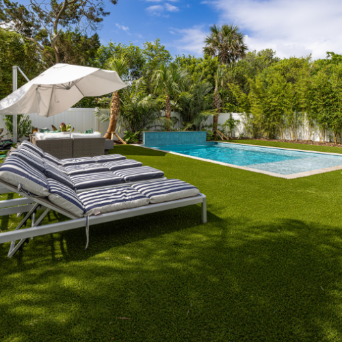 Custom swimming pool surrounded by lush landscaping and outdoor seating