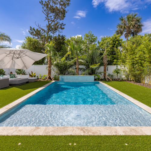 Custom swimming pool surrounded by lush landscaping and outdoor seating
