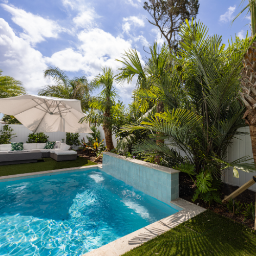 Custom swimming pool surrounded by lush landscaping and outdoor seating