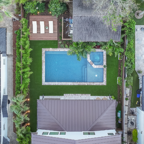 Custom swimming pool surrounded by lush landscaping and outdoor seating