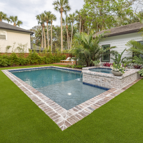 Custom swimming pool surrounded by lush landscaping and outdoor seating